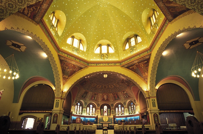 interior of church with large gold dome, Byzantine-style religious paintings and decorated arches