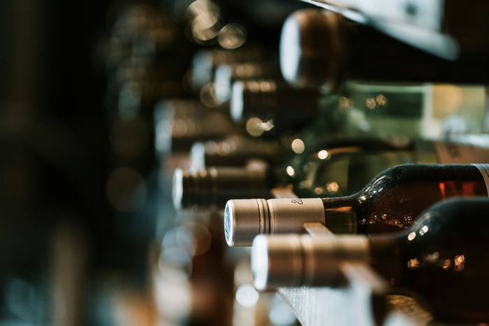 A wine bottle lying flat in a rack, with blurred bottles of wine around it.