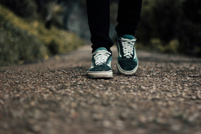 closeup of legs in black leggings and feet in green running shows walking along a gravel trail