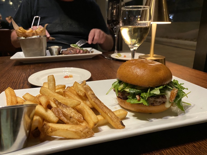 chelsea hotel burger - Ottawa Road Trips oblong white plate with french fries and a burger, with glass of white wine
