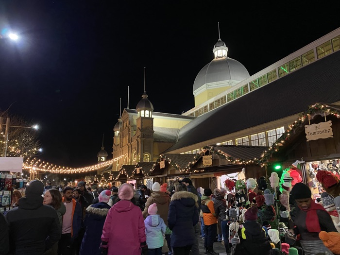crowds walking past wooden stalls at ottawa christmas market at lansdowne park.