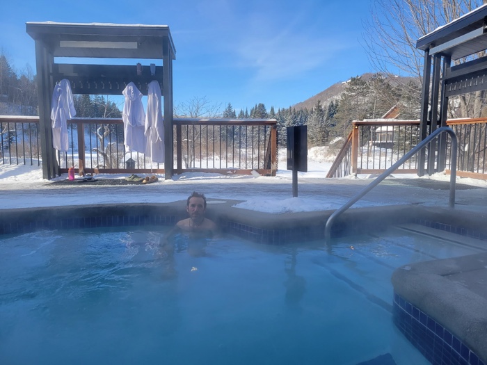 dan at strøm spa saint-sauveur sized - Ottawa Road Trips man in an outdoor thermal pool surrounded by snow, with small mountain in background