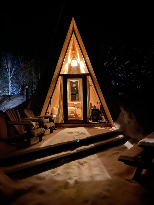 farouche tremblant 5 sized - Ottawa Road Trips small illuminated a-frame cabin at night, with snowy deck in foreground and trees behind
