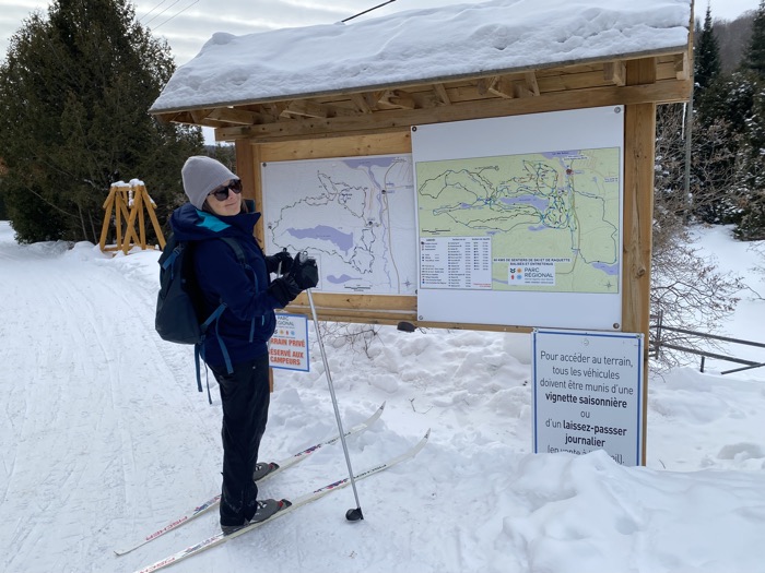 lisa at parc régional de sainte-agathe-des-monts sized - Ottawa Road Trips woman on skis looking at a large outdoor trail map