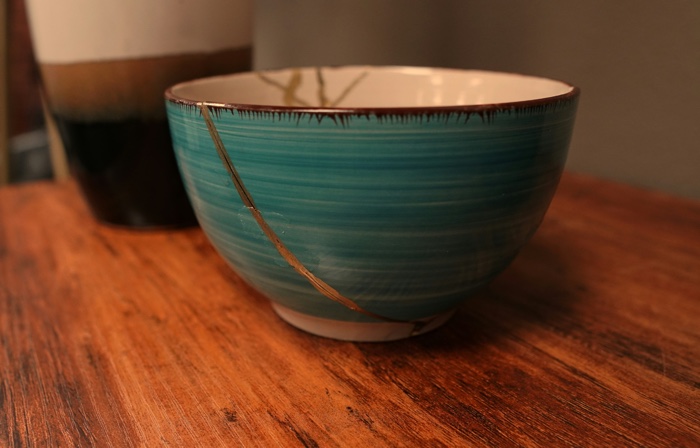 striped green ceramic bowl with crack repaired with gold