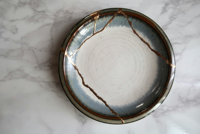 riho-kitagawa-kintsugi-unsplash - Ottawa Road Trips earth-toned pottery plate with multiple cracks repaired with gold