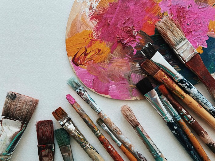 jennie-razumnaya-art brushes 2026-unsplash - Ottawa Road Trips a selection of artist brushes next to a palette with pink and orange paint