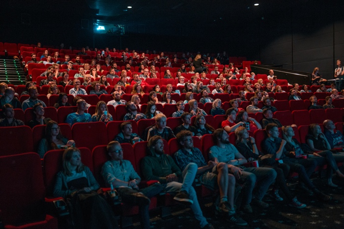 krists-luhaers-movie theatre cinema-unsplash - Ottawa Road Trips audience sitting in red seats in a movie theatre