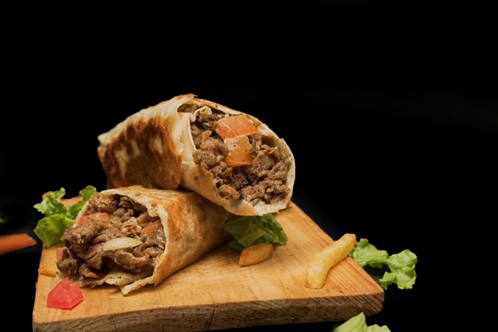 two shawarma wraps on a wooden cutting board
