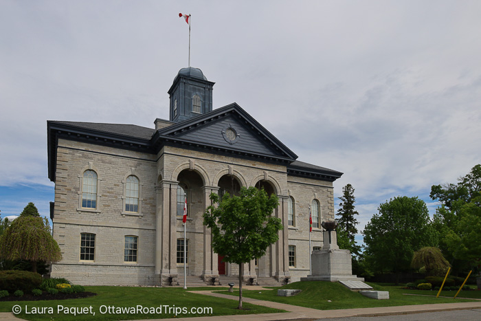 large limestone building with arched windows and a cupola with a flag