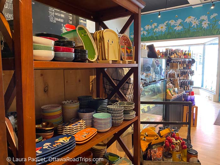 colourful dishes on wooden shelves with bakery case in background