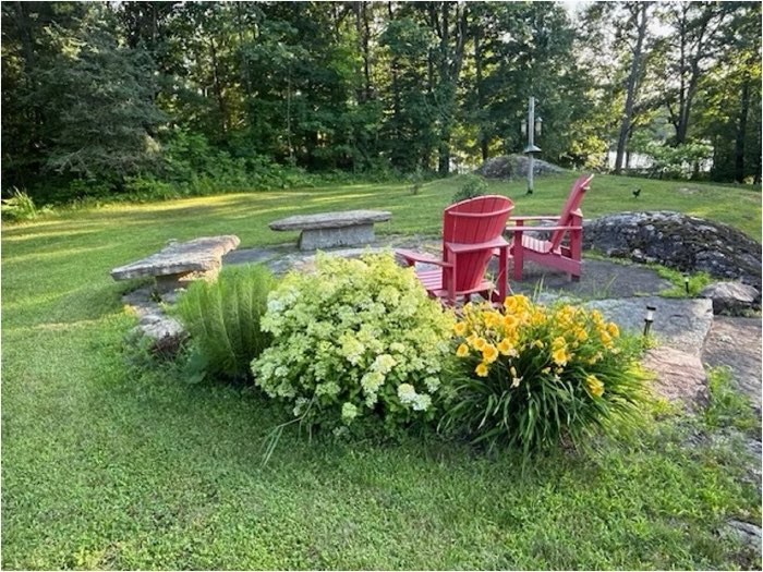 perth garden tour 700 - Ottawa Road Trips two red muskoka chairs surrounded by flowers and stone walls, with water in the background