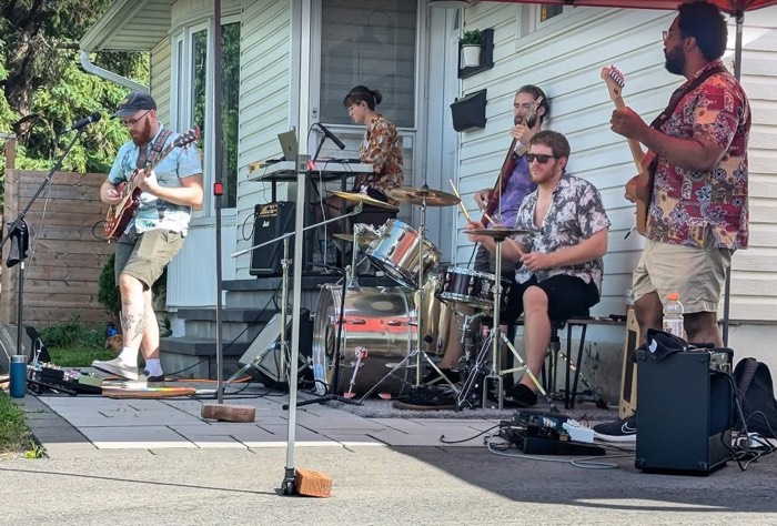 five musicians playing on a paved patio by a house's front door