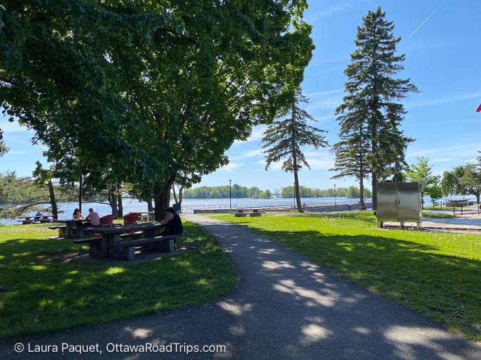 picnic tables shaded by trees beside the st. lawrence river