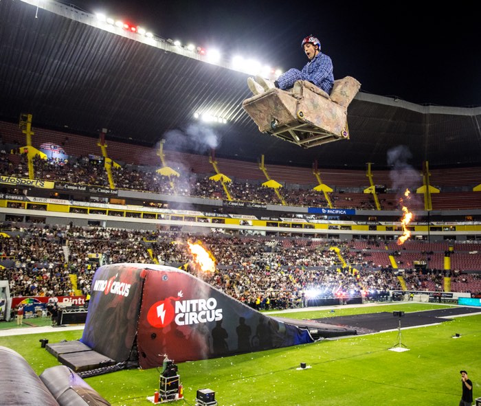 man in recliner soaring above ramp and fire