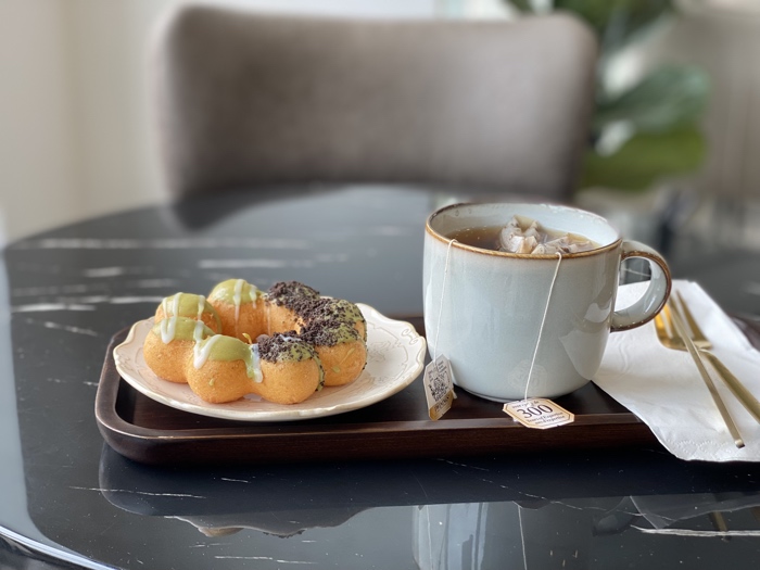 a mochi donut and a mug of tea on a wooden tray