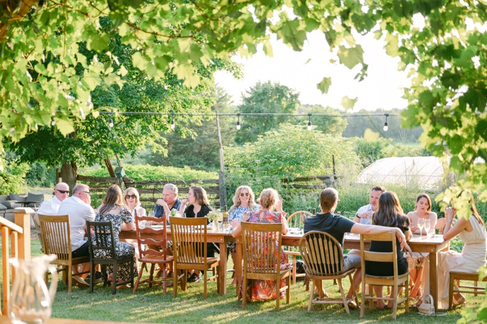 people eating lunch at a long table outdoors.