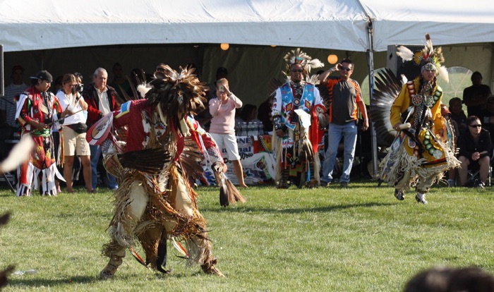 akwesasne powwow 2009 984 sized - Ottawa Road Trips indigenous men in ceremonial dress dancing outdoors as people take photos