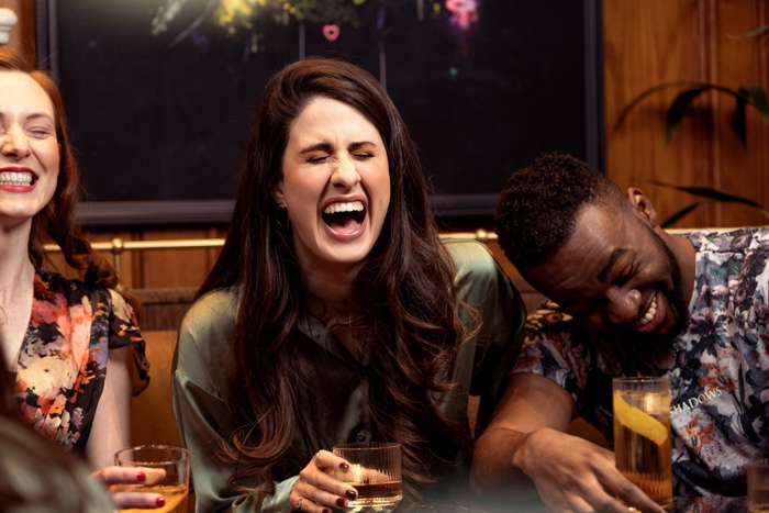 ourwhisky-foundation-laughing-unsplash - Ottawa Road Trips three friends at a bar laughing, holding drinks and enjoying a night out.